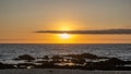 Beautiful sunset over ocean with bright orange sky and shining sun behind cloud on horizon Royalty Free Stock Photo