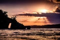 Beautiful sunset over the ocean with small island. Sun passing behind clouds with sunrays. Bali Royalty Free Stock Photo