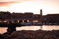 Beautiful sunset over the old town of Dubrovnik. Small local harbour in front of the city, woman in black clothes sitting on a Royalty Free Stock Photo