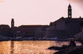 Beautiful sunset over the old town of Dubrovnik. Small local harbour in front of the city, woman in black clothes sitting on a Royalty Free Stock Photo