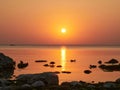 Beautiful sunset over rocky shore of sea with silhouettes of stones and ducks Royalty Free Stock Photo