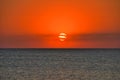 Beautiful sunset over the surface of the sea in red, a horizon line, a small cloud cover