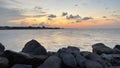 Beautiful sunset over tropical sea, wispy clouds with pile of rocks as foreground photo Royalty Free Stock Photo