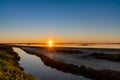 Sunset over wetlands and marshlands with a colorful sky and a sun star on the horizon Royalty Free Stock Photo