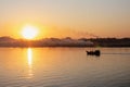 Beautiful sunset on the river. Silhouette of a fishing boat going towards the sun. Mysterious fog and smoke at the horizon. Royalty Free Stock Photo