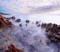 Beautiful sunset at romantic tropical beach cove with stones and water in motion Royalty Free Stock Photo