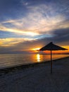 Beautiful sunset on the sandy beach. Straw umbrella by the sea, calm, beautiful natural background. Royalty Free Stock Photo