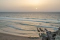 Beautiful sunset at the sandy shore in of the calm Atlantic ocean. Long foamy waves approaching sandy beach Royalty Free Stock Photo