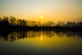 Beautiful sunset scenery over the lake with silhouettes of trees reflected in the water Royalty Free Stock Photo