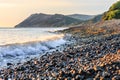 Beautiful sunset scenery with wave breaking on stony seashore. Scenic landscape of Black Sea coast in Caucasus Mountains by Royalty Free Stock Photo