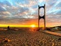 Sunset at sea maritime bridge gate in the sun light beach people walking romantic couple stay on sand reflection on sea