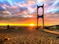 Beautiful sunset at sea maritime bridge gate in the sun light beach people walking romantic couple stay on sand reflection on sea