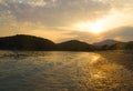 Beautiful sunset at the seaside with mountains on background. The sun breaks through the clouds. A stream of light appears from Royalty Free Stock Photo