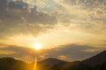 Beautiful sunset at the seaside with mountains on background. The sun breaks through the clouds. A stream of light appears from Royalty Free Stock Photo