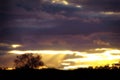 Beautiful sunset, the setting sun on a background of purple storm clouds. Dark clouds hide the rays of light coming from behind Royalty Free Stock Photo