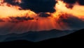 Beautiful sunset sky with dramatic sun rays over a mountain landscape Royalty Free Stock Photo