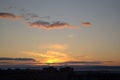 Beautiful sunset sky with small clouds illuminated by the sun's rays over the silhouette of city blocks. Royalty Free Stock Photo