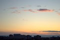 Beautiful sunset sky with small clouds illuminated by the sun's rays over the silhouette of city blocks. Royalty Free Stock Photo