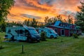 Beautiful sunset at a Swedish campground in the forest with a red cottage and camper vans in the foreground