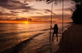 Beautiful sunset tropical beach, The girl is happiness swinging on a swing Royalty Free Stock Photo