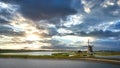 Beautiful sunset view with clouds over a river with rural windmill in natural landscape Royalty Free Stock Photo