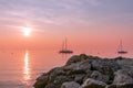 Beautiful sunset view during fog on Lake Garda with sailing boats and textured stones in the foreground. Lake garda, Italy Royalty Free Stock Photo