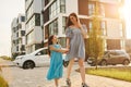 Beautiful sunshine. Young mother with her little daughter walking near the buildings Royalty Free Stock Photo