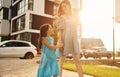 Beautiful sunshine. Young mother with her little daughter walking near the buildings Royalty Free Stock Photo