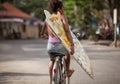 Beautiful surfer girl in purple bikini with afro hairstyle riding bicycle with one hand Royalty Free Stock Photo