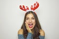 Beautiful surprised christmas girl with reindeer horns on her head with gray background