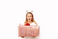 Beautiful surprised kid girl holding a Christmas red striped gift box with a ribbon and a bow in her hands. There are snowflakes Royalty Free Stock Photo