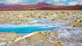 Beautiful surreal desert pan landscape, blue natural water pool, white dry salt crust flat, red mountains volcano Licancabur Royalty Free Stock Photo