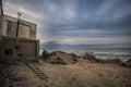 Beautiful surreal landscape of abandoned house and ladder on rocky seashore at sunset time. Cloudy weather. Caspian Sea, Azerbaija Royalty Free Stock Photo