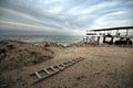 Beautiful surreal landscape of abandoned house and ladder on rocky seashore at sunset time. Cloudy weather. Caspian Sea, Azerbaija Royalty Free Stock Photo