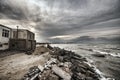 Beautiful surreal landscape of abandoned house and ladder on rocky seashore at sunset time. Cloudy weather. Caspian Sea, Azerbaija Royalty Free Stock Photo