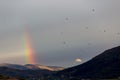 Beautiful and surreal view of a small rainbow over some hills, w