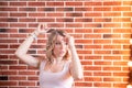 Beautiful swag style dressed girl in short jeans at textured red bricks wall background Royalty Free Stock Photo