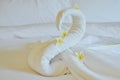 Beautiful swan from white bath towel decorate on white bed. towel swan with topical flowers - frangipani. Nice greeting from Hotel Royalty Free Stock Photo