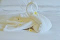 Beautiful swan from white bath towel decorate on white bed. towel swan with topical flowers - frangipani. Nice greeting from Hotel Royalty Free Stock Photo