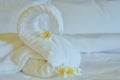 Beautiful swan from white bath towel decorate on white bed. towel swan with topical flowers - frangipani. Nice greeting from Hotel Royalty Free Stock Photo