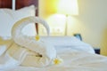 Beautiful swan from white bath towel decorate on white bed. towel swan with topical flowers - frangipani. Nice greeting from Hotel Royalty Free Stock Photo