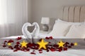 Beautiful swans made of towels and red rose petals on bed in five star hotel room, closeup Royalty Free Stock Photo