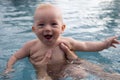 Beautiful, sweet baby boy swimming in the swimming pool holding fathers hands. Royalty Free Stock Photo