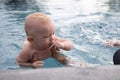 Beautiful, sweet baby boy swimming in the swimming pool holding fathers hands. Royalty Free Stock Photo