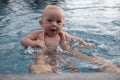 Beautiful, sweet baby boy swimming in the swimming pool holding fathers hands. Royalty Free Stock Photo