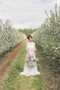 Beautiful sweet gentle happy girl in a beige boudoir dress with flowers in a basket holding , photo processing in the style of mod