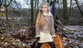 Beautiful sweet little girl dressed in a sheepskin coat and boots sitting on the trunk and in the background Royalty Free Stock Photo