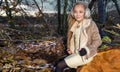 Beautiful sweet little girl dressed in a sheepskin coat and boots sitting on the trunk and in the background Royalty Free Stock Photo