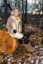 Beautiful sweet little girl dressed in a sheepskin coat and boots sitting on the trunk and in the background Royalty Free Stock Photo