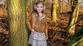 Beautiful sweet little girl dressed in a sheepskin coat and boots sitting on the trunk and in the background Royalty Free Stock Photo